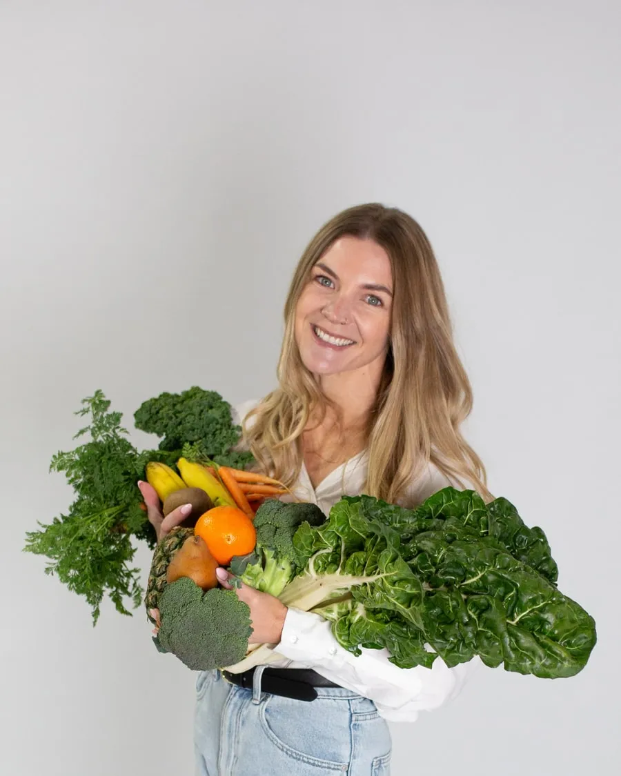 Natalie holding an armful of fresh vegetables